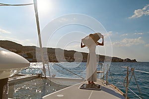 Beautiful woman wearing straw hat and white dress on a yacht enjoys the journey, Spetses, Greece, Europe