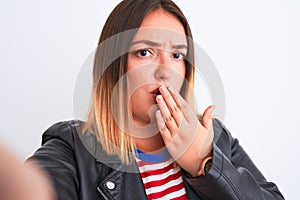 Beautiful woman wearing striped shirt and jacket make selfie over isolated white background cover mouth with hand shocked with