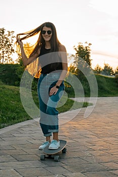beautiful woman wearing sunglasses and casual clothes riding skateboard