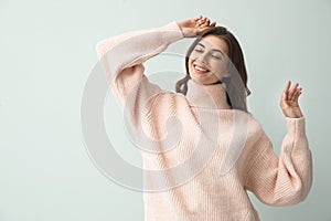 Beautiful woman wearing warm pink sweater on light background. Space for text