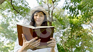 Beautiful woman wearing white shirt and white hat Enjoying a Book Reading.Concept of recreation, education and study , curiosity,