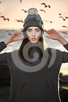 Beautiful woman wearing winter clothes standing on the beach