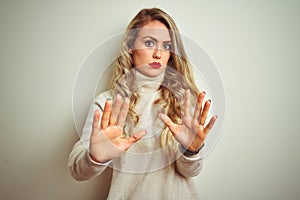 Beautiful woman wearing winter turtleneck sweater over isolated white background Moving away hands palms showing refusal and