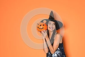 Beautiful woman wearing witch costume with Jack O`Lantern candy container for Halloween party on background, space for tex