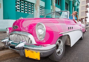 The beautiful woman at a wheel old American retro car (50th years of the last century), an iconic sight in the city, on the