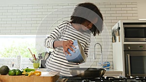 Beautiful woman whisking batter and pouring into hot pan, young mixed race woman baking in the kitchen