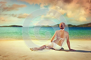 Beautiful woman in white bikini sunbathing on the beach on the b