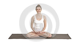 Beautiful woman in white clothers sitting on yoga mat and talking to camera on white background.