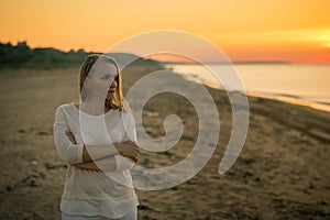 Beautiful woman in white clothes enjoying the sunset on the beach.