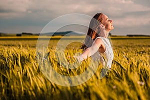 Beautiful woman in white dress on golden yellow wheat field