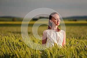 Beautiful woman in white dress on green wheat field