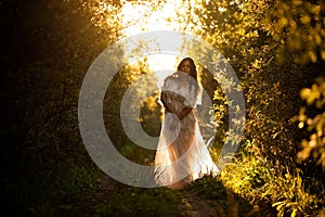 Beautiful woman in a white dress at sunset