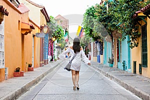 Beautiful woman on white dress walking alone at the colorful streets of the colonial walled city of Cartagena de Indias photo