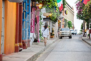 Beautiful woman on white dress walking alone at the colorful streets of the colonial walled city of Cartagena de Indias photo