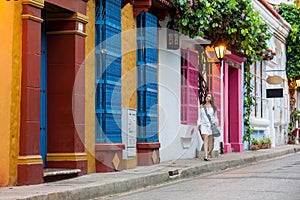 Beautiful woman on white dress walking alone at the colorful streets of the colonial walled city of Cartagena de Indias photo