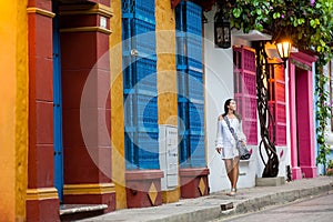 Beautiful woman on white dress walking alone at the colorful streets of the colonial walled city of Cartagena de Indias photo