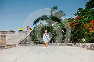 Beautiful woman on white dress walking alone at the walls surrounding the colonial city of Cartagena de Indias photo