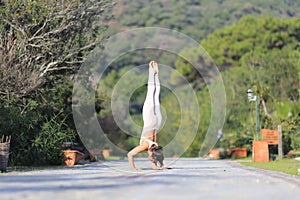 A beautiful woman in a white gymnastic jumpsuit is engaged in yoga.