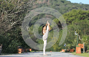 A beautiful woman in a white gymnastic jumpsuit is engaged in yoga.