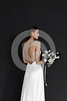 Beautiful woman in a white wedding dress on a black background. A modern trendy bride in an elegant dress.