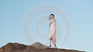 beautiful woman in white wedding dress sings into retro microphone at dawn or sunset sunrise. Cheerful young lady