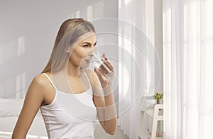 Beautiful woman who likes to stay hydrated is drinking purified water from glass