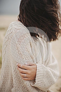 Beautiful woman with windy hair sitting on sandy beach on background of sea, calm tranquil moment. Closeup of stylish young female