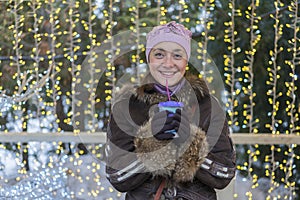 Beautiful woman in winter clothes with coffee in hand On the background of beautiful bokeh. outdoor