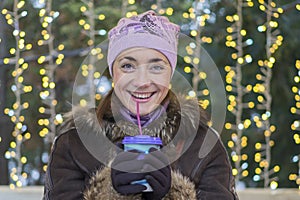 Beautiful woman in winter clothes with coffee in hand On the background of beautiful bokeh. outdoor