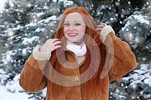 Beautiful woman on winter outdoor, snowy fir trees in forest, long red hair, wearing a sheepskin coat