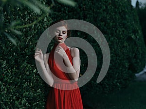 Beautiful woman woman in red dress outdoors near bush luxury charm