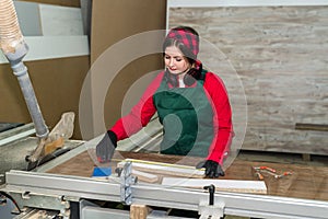 Beautiful woman woodworker in uniform measuring wooden plank