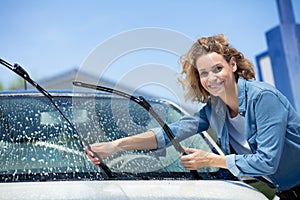 beautiful woman worker washing windshield