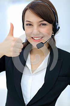 Beautiful woman working at callcenter, using headset showing thu