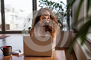 Beautiful woman working on laptop at home, homeoffice for young worker. Student studying at home, preparing for final photo