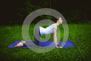 Beautiful woman working out yoga excercises mardzhariasana on fitness mat