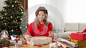 Beautiful woman wrapping Christmas gift at home