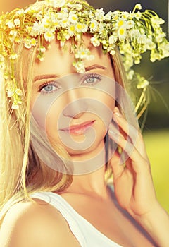 Beautiful woman in wreath of flowers lies in the green grass out