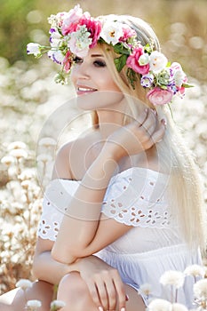 Beautiful woman with a wreath of flowers in summer field