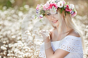 Beautiful woman with a wreath of flowers in summer field