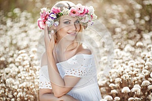 Beautiful woman with a wreath of flowers in summer field