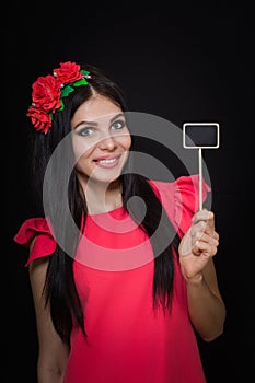 Beautiful woman with a wreath of red flowers holds a wooden plaque