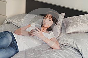 Beautiful woman writes sms on smartphone in white tshirt and blu