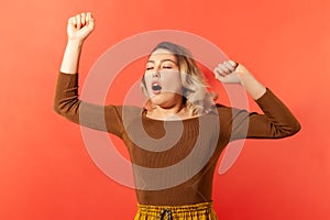 Beautiful woman yawning with closed eyes and raised arm