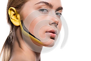 beautiful woman with yellow and black paints on ear and face