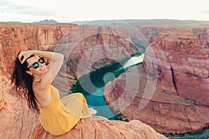 Beautiful woman in yellow dress on the edge of the cliff at Horseshoe Band Canyon in Paje, Arizona. Beautiful nature in