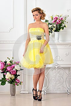 Beautiful woman in yellow dress in luxury studio.
