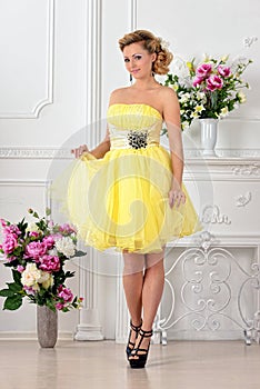 Beautiful woman in yellow dress in luxury studio.