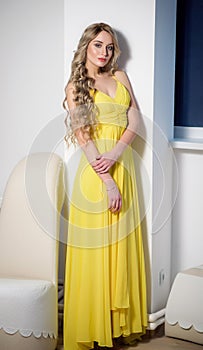Beautiful woman in a yellow evening dress. Beauty portrait of a model with a hairstyle