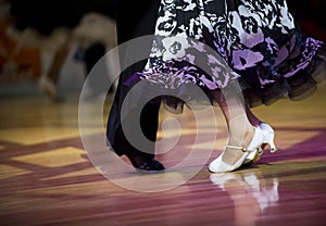 Beautiful womanish and masculine legs in active ballroom dance, indoors